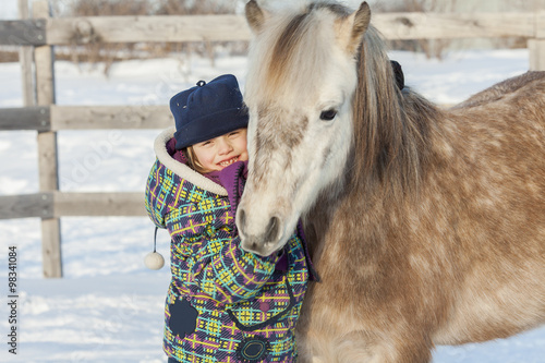 Little girl with horse outdoor in winter