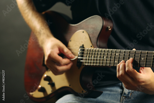 Young musician playing electric guitar close up