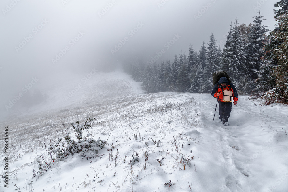 Backpacker walking on winter moutain scene
