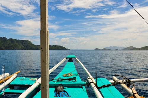Tip of a wooden filipino Boat Facing the blue ocean and sky with clouds