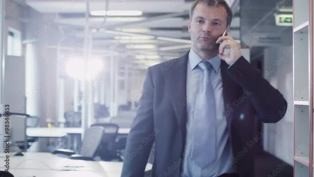 Businessman on the Phone in Walking through Office. Shot on RED Cinema Camera. Businessman on the Phone in Walking through Office. Shot on RED Cinema Camera.