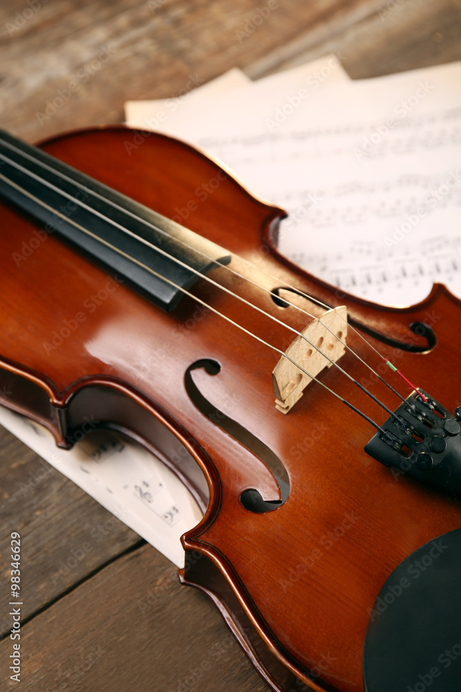 Violin and music papers on wooden background Violin and music papers on wooden background