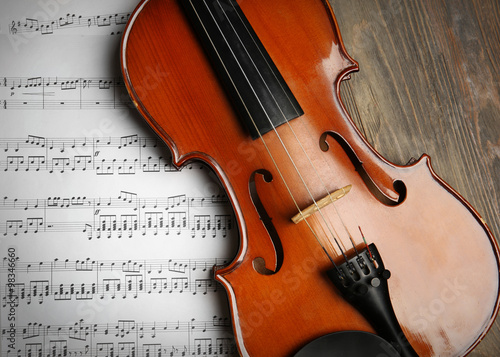 Violin and music papers on wooden background