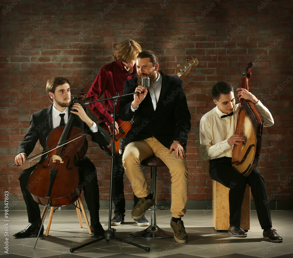 Fototapeta premium Man's musical band on brick wall background in the studio