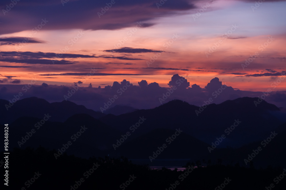 Silhouette of Mountains Above the Water under purple cloudscape clouds at sunset
