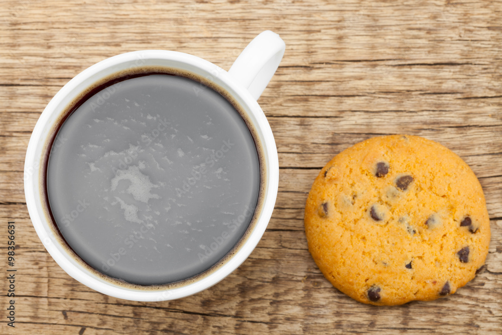 Close up of coffee cup and cookie on old wooden table Close up of coffee cup and cookie on old wooden table