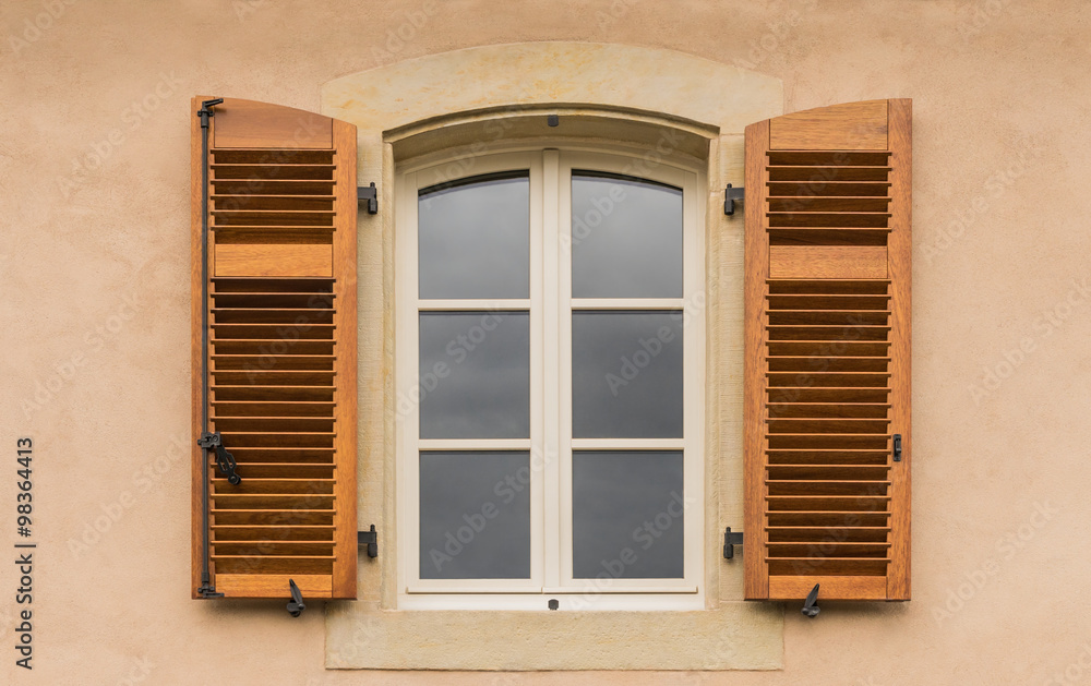 Offener Klappladen aus naturfarbenem Holz an modernem Holzbogenfenster mit weißer Lackierung 