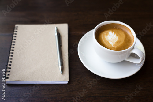 Coffee cup and notebook on grunge wooden background.