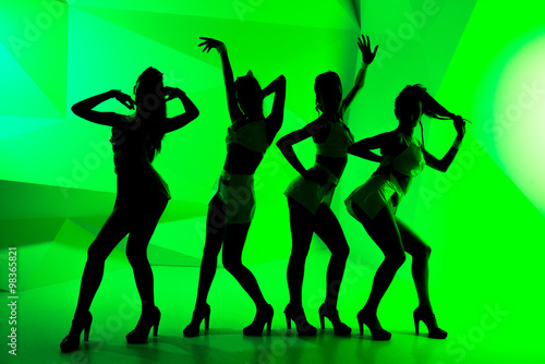 Black silhouettes of dancing girls on green background
