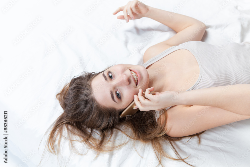 Fototapeta premium The young girl in bed with phone
