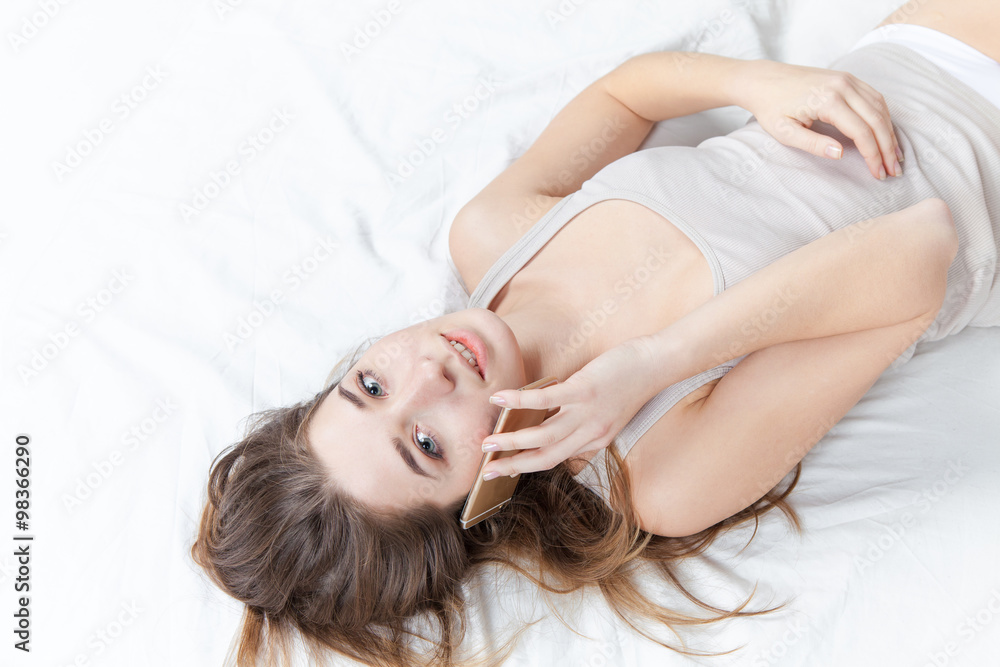 The young girl in bed with phone The young girl in bed with phone