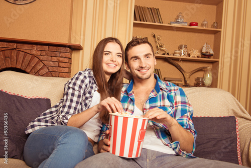 Couple enjoying watching a movie at home laughing on the couch