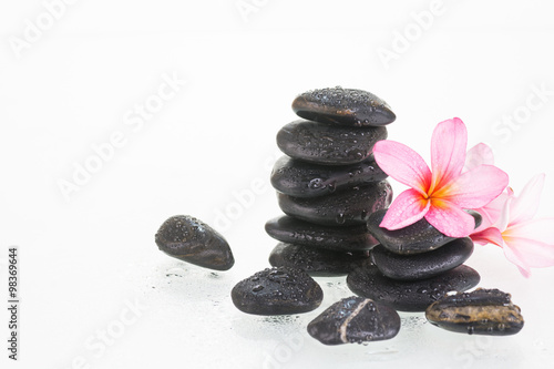 Plumeria flowers and black stones over white background 