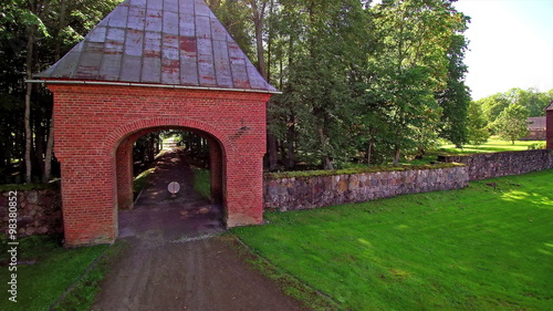 The red gate house of the Alatskivi manor in Estonia. The entrance gate going inside the manor in the middle of the forest photo