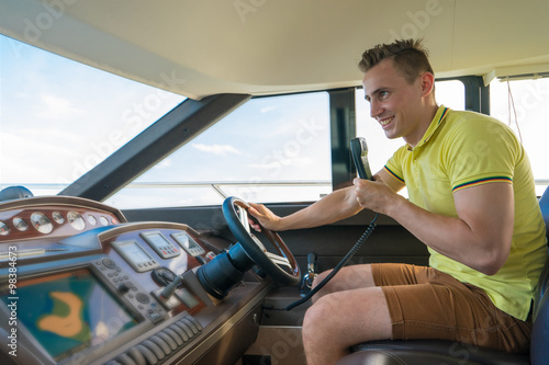  Happy man drive and talk on radio on luxury boat yacht.