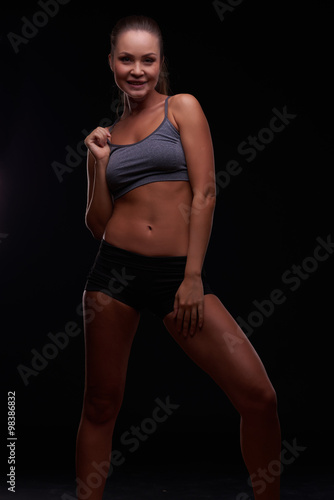 Beautiful young girl on a dark background is engaged in fitness © legull