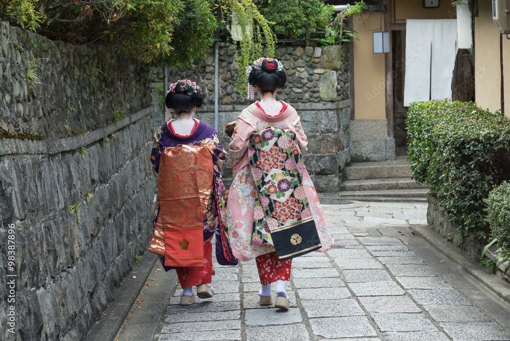 Two geishas walking on a street in the evening, Kyoto Japan