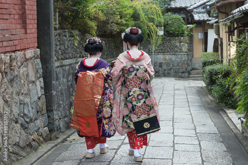 Two geishas walking on a street in the evening, Kyoto Japan