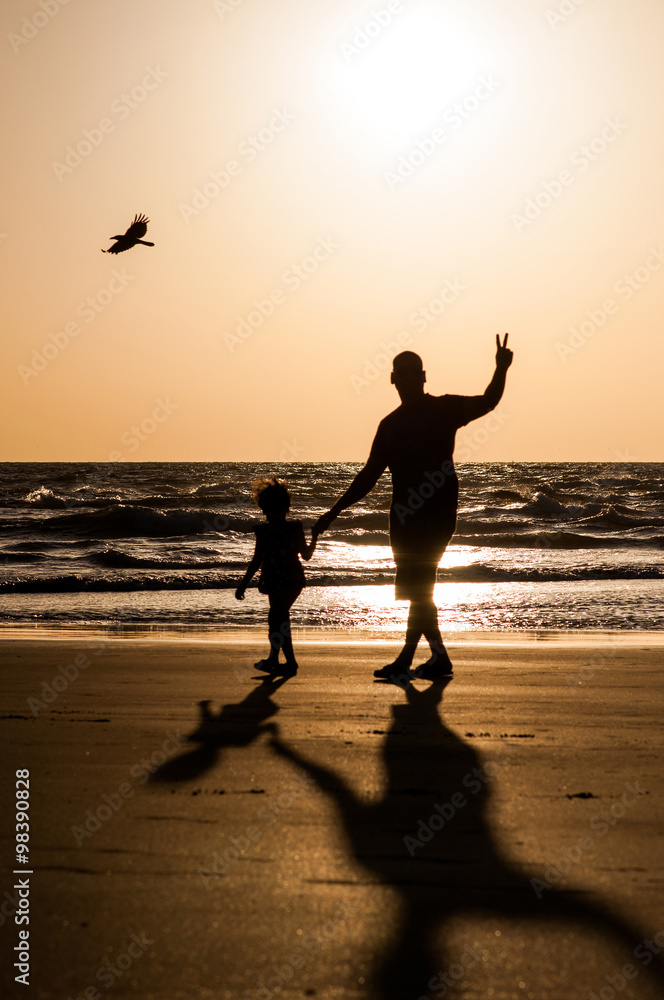 father and daughter on the beach at sunset