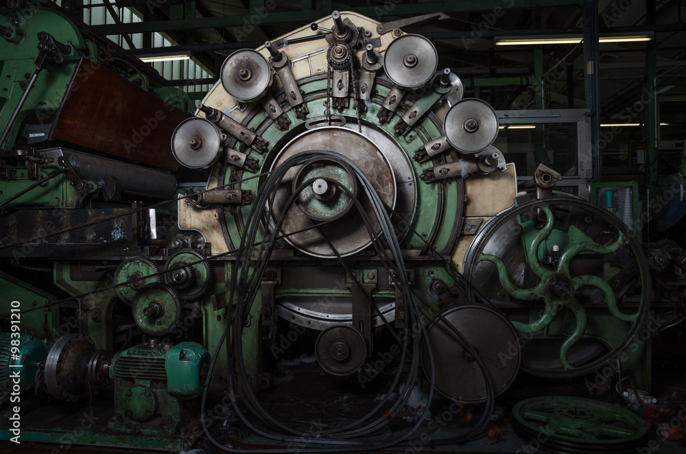 Old 1960s industrial cotton working machine in a dark factory atmosphere