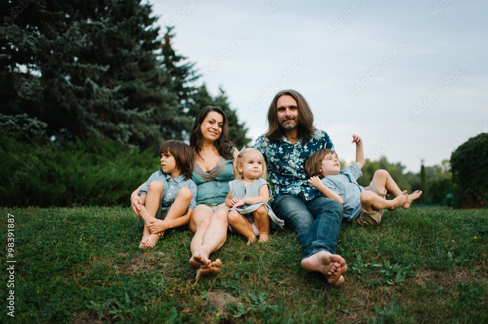 Fototapeta premium Happy young hipster family having fun, bowl, rising up, piggyback ride their children in park on summer sunset