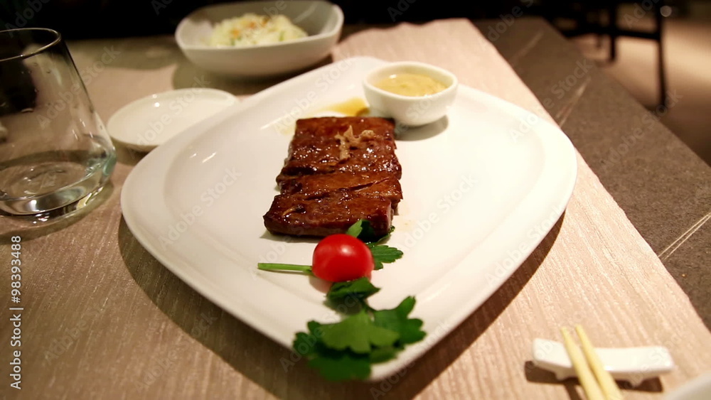 man eating japanese rice in background and in first view a plate of seared tuna on iron plate, in a japanese restaurant man eating japanese rice in background and in first view a plate of seared tuna on iron plate, in a japanese restaurant