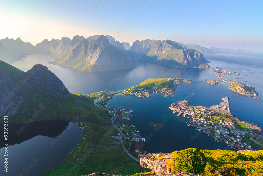 Aerial view of small seaside town situated at the foot of a mountain,bridge, green islands and sea at sunset  in Norway