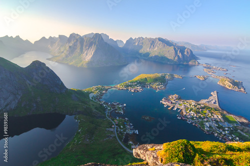 Aerial view of small seaside town situated at the foot of a mountain,bridge, green islands and sea at sunset  in Norway