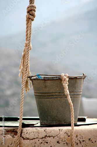 close up of old fashioned stone well with bucket and rope photo