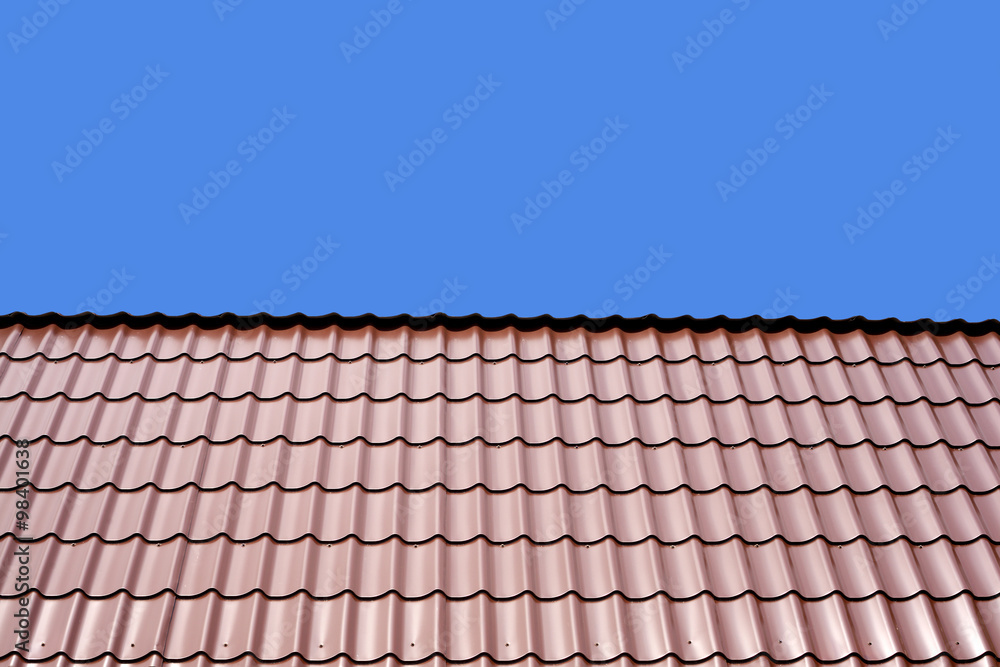 Gable roof of a house covered with metal tile isolated on blue background closeup