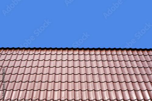 Gable roof of a house covered with metal tile isolated on blue background closeup