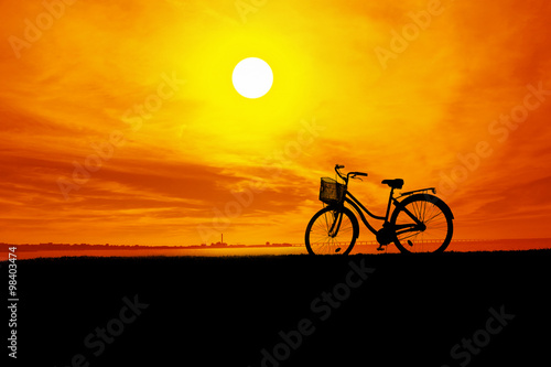 Fototapeta Naklejka Na Ścianę i Meble -  The silhouette of the bike and orange sky at sunset.