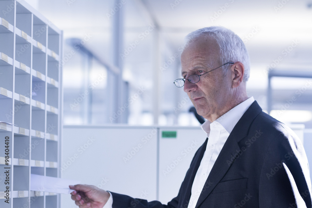 Businessman at pigeonhole in office Businessman at pigeonhole in office