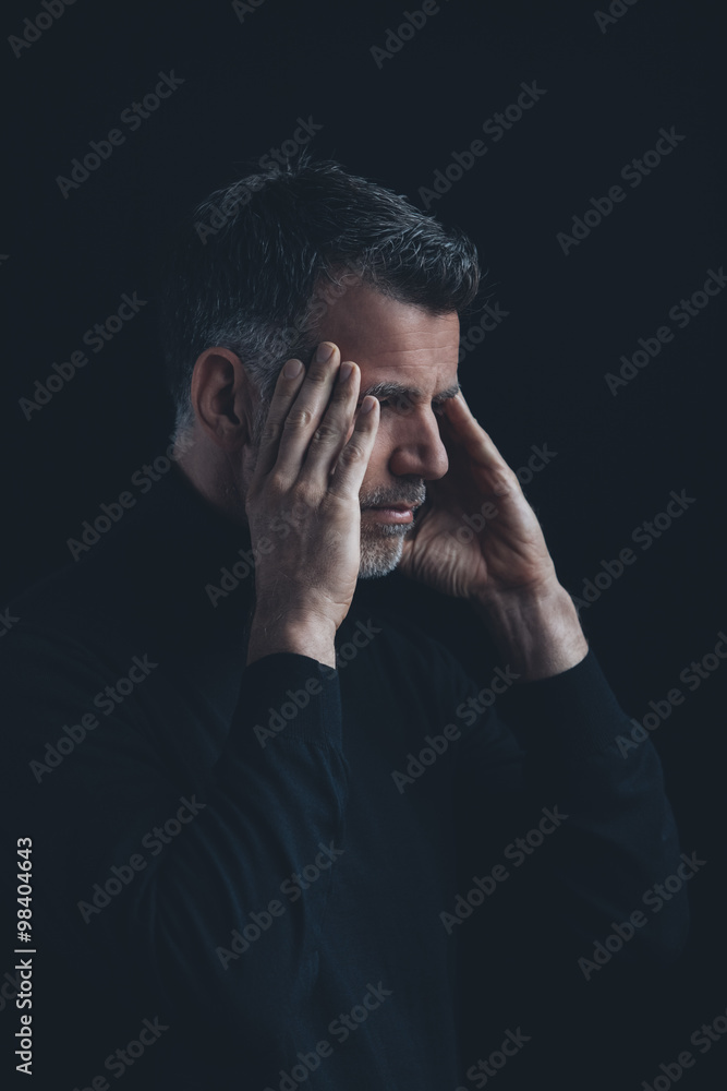 Portrait of man with hands on his temples in front of black background Portrait of man with hands on his temples in front of black background