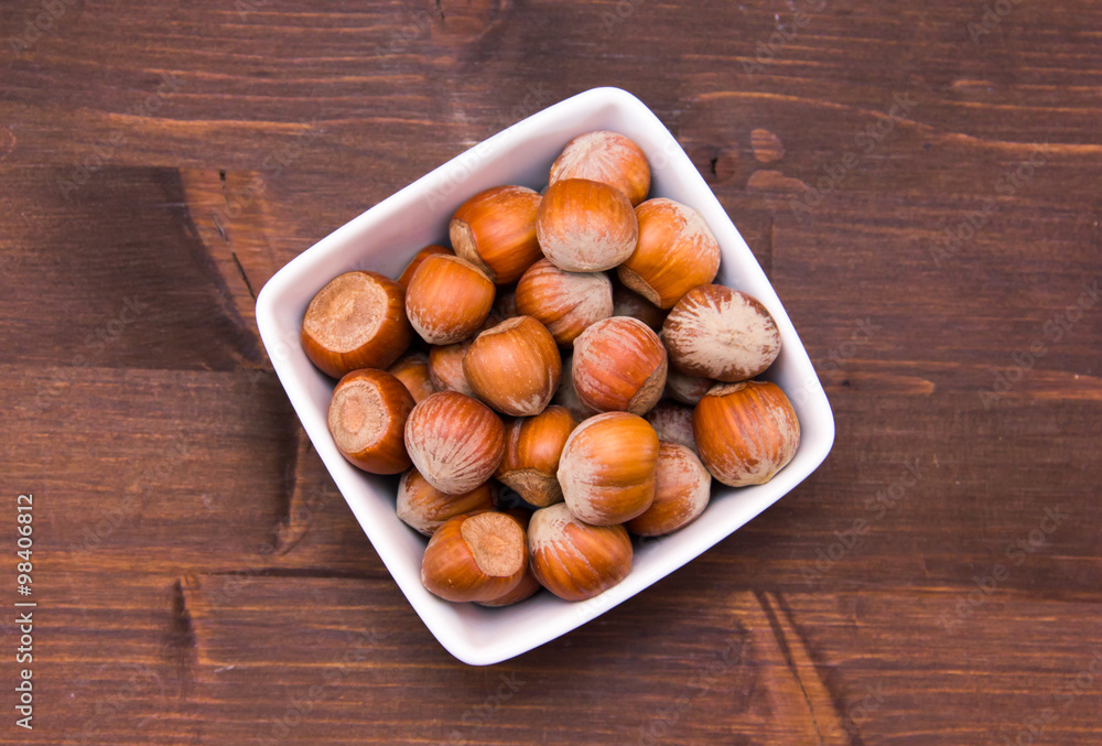 Hazelnuts on square bowl on wooden table top views