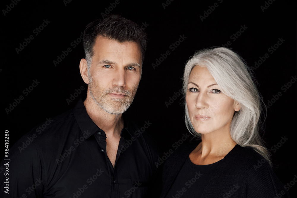 Portrait of mature man and mature woman wearing black clothes in front of black background Portrait of mature man and mature woman wearing black clothes in front of black background