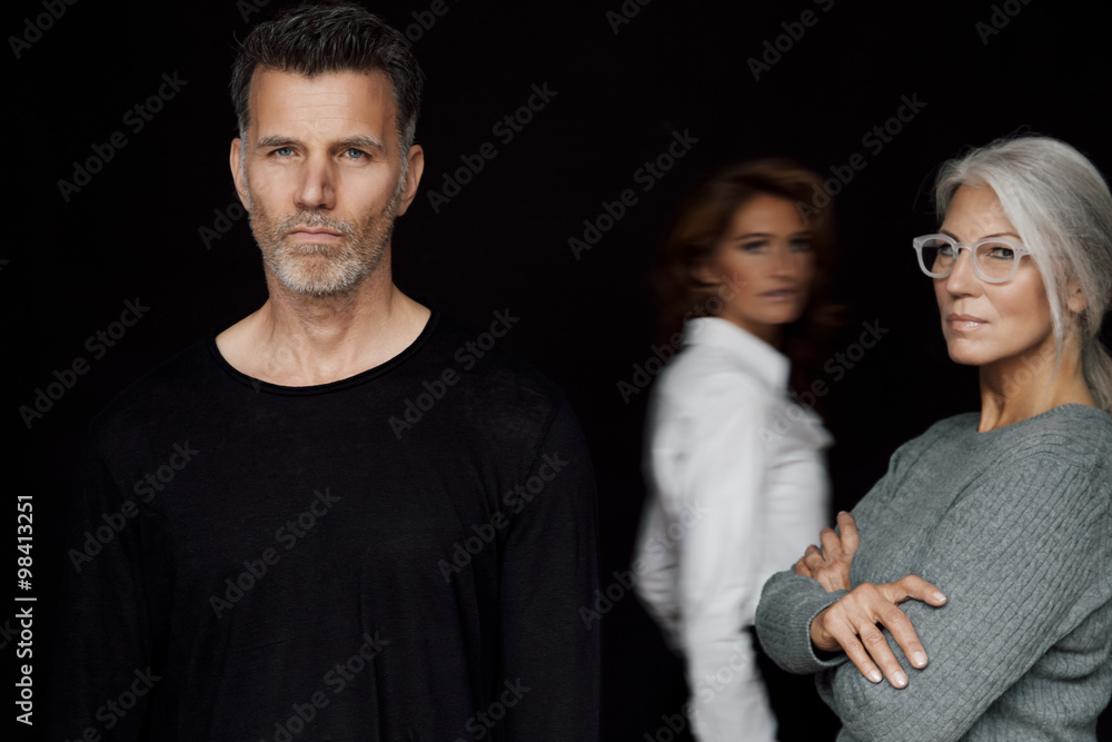 Portrait of serious looking business people in front of black background Portrait of serious looking business people in front of black background
