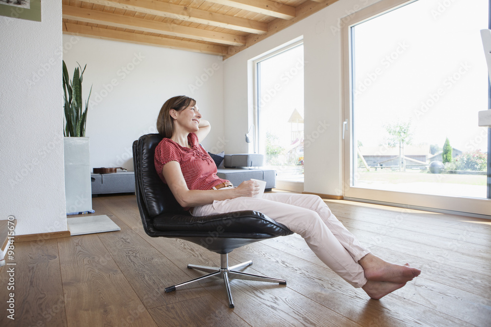 Mature woman sitting relaxed in her living room, drinking coffee Mature woman sitting relaxed in her living room, drinking coffee
