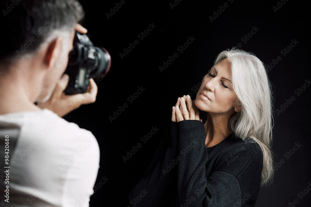 Man photographing woman in front of black background Man photographing woman in front of black background