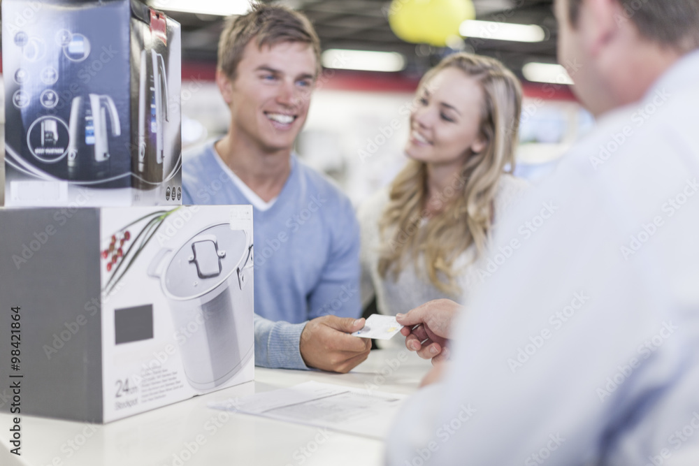 Young couple at counter in shop paying for purchase Young couple at counter in shop paying for purchase