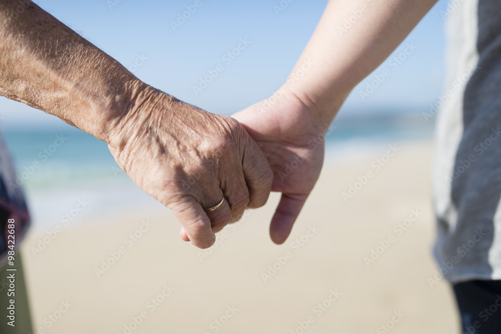 Elderly woman and young woman holding hands on the beach Elderly woman and young woman holding hands on the beach