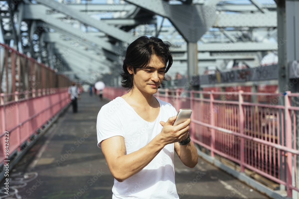 USA, New York City, man on Williamsburg Bridge in Brooklyn checking the cell phone USA, New York City, man on Williamsburg Bridge in Brooklyn checking the cell phone