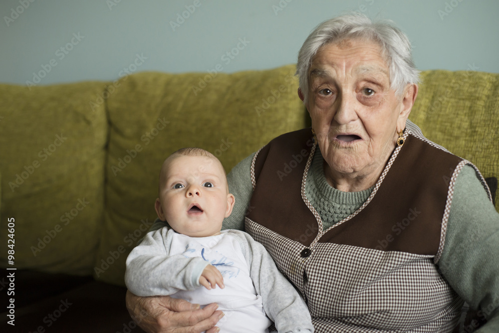 Old woman and her great-grandson sitting on the couch Old woman and her great-grandson sitting on the couch