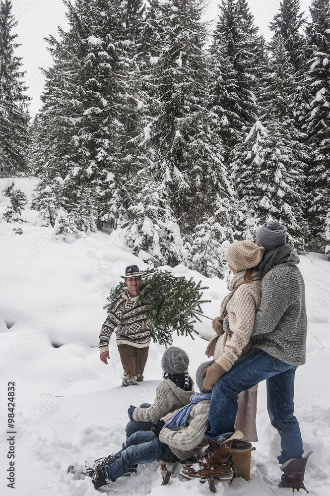 Austria, Altenmarkt-Zauchensee, man with Christmas tree and family together  in winter forest Stock-Foto | Adobe Stock