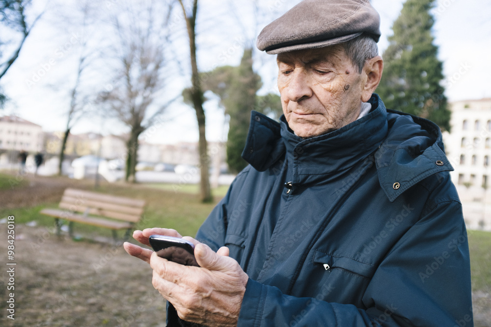 Portrait of senior man with smartphone in a park Portrait of senior man with smartphone in a park