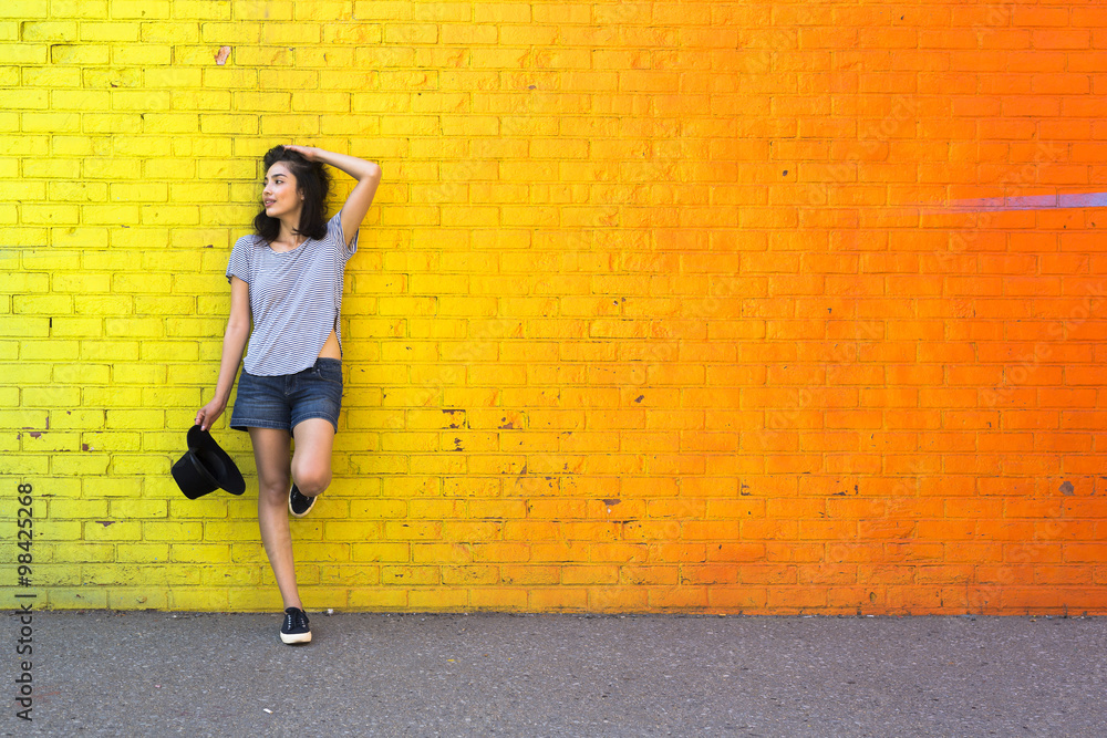 Young woman leaning against yellow brick wall Young woman leaning against yellow brick wall