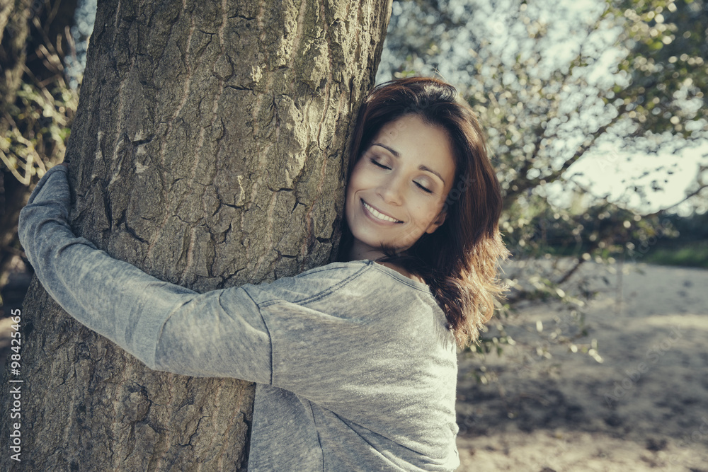 Portrait of smiling woman with closed eyes hugging a tree Portrait of smiling woman with closed eyes hugging a tree