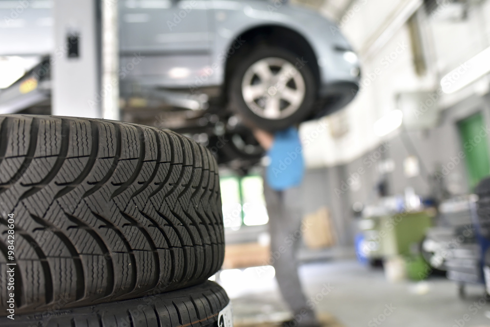 Car mechanic in a workshop, car tires in the foreground Car mechanic in a workshop, car tires in the foreground