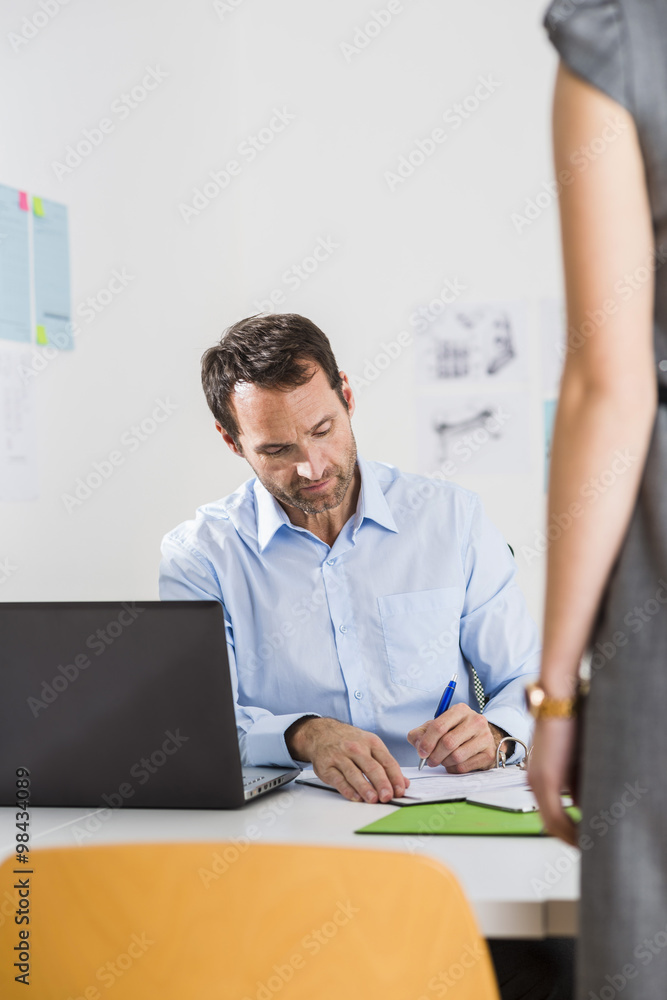 Businessman in office signing document Businessman in office signing document
