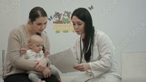 female pediatrician doctor shows some papers to woman with small baby